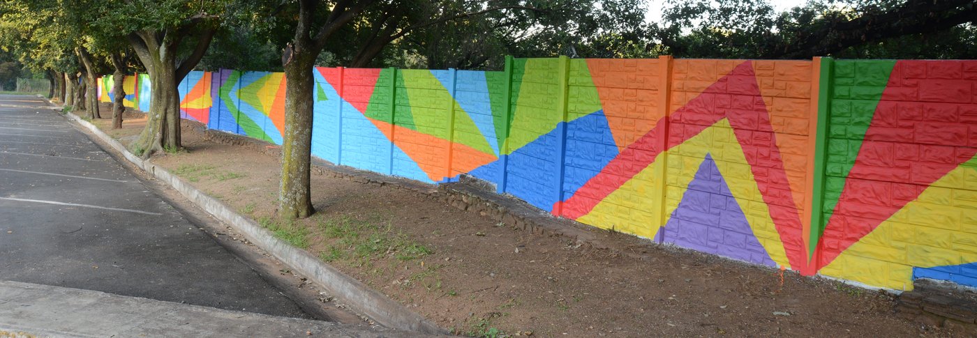 Finished geometric rainbow mural along a tree-lined street wall